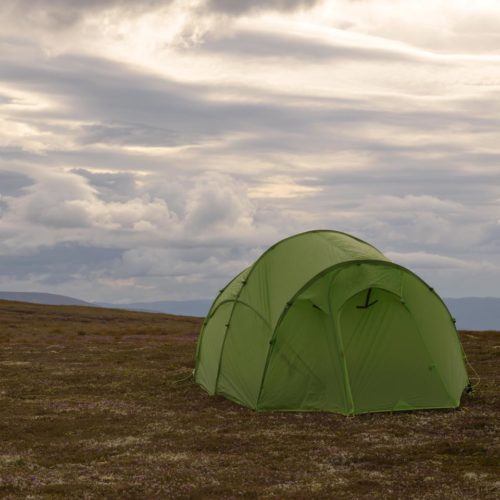 Quadratic tent pitched on a plateau with clouds behind